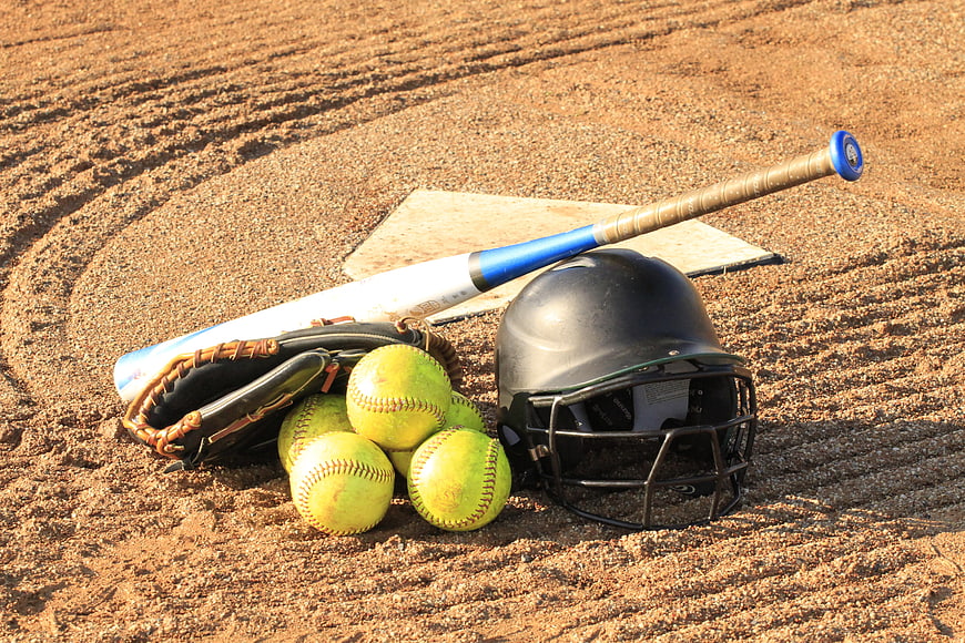Softball equipment on dirt field with helmet and bat