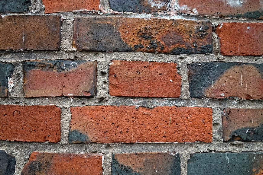 Close-up of weathered red brick wall with rough texture