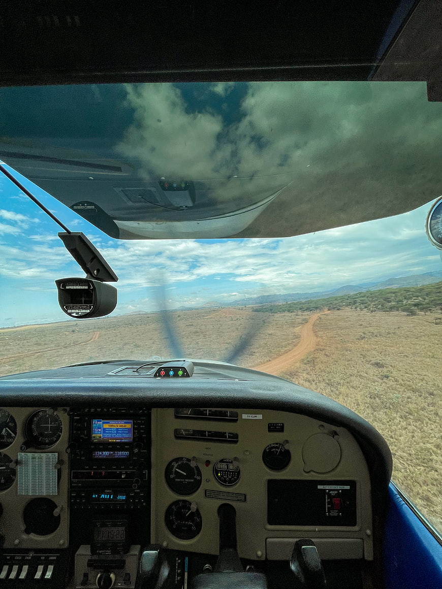 Cockpit View of Small Aircraft Flying Over Savanna