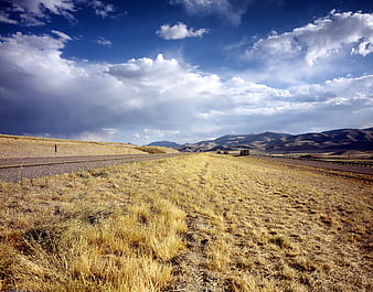 Scenic rural highway through golden fields and mountains