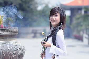 Smiling Woman in White Top Holding Lotus Flower at Temple