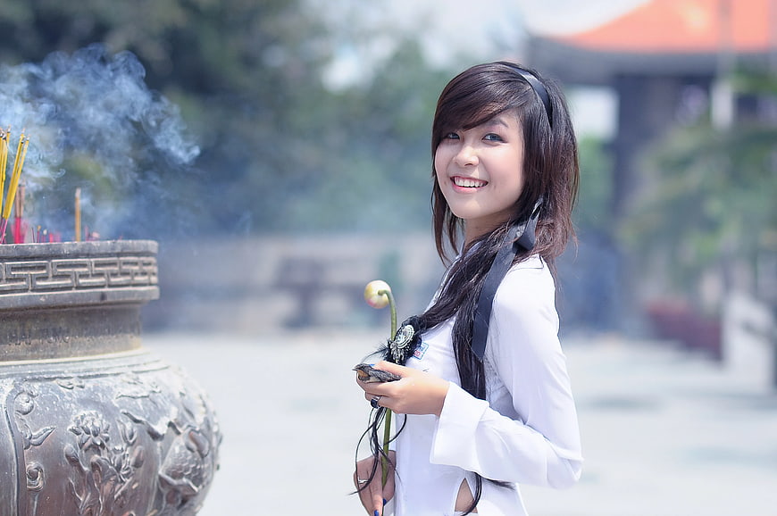 Smiling Woman in White Top Holding Lotus Flower at Temple