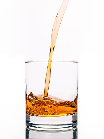 Amber Whisky Pouring Into Clear Glass Tumbler On White Background