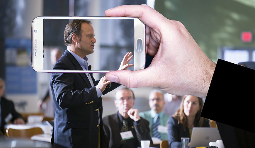Man recording business conference speaker with smartphone