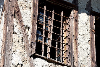 Old wooden window with bars on a rustic stone wall