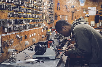Locksmith working with key cutting machine in workshop