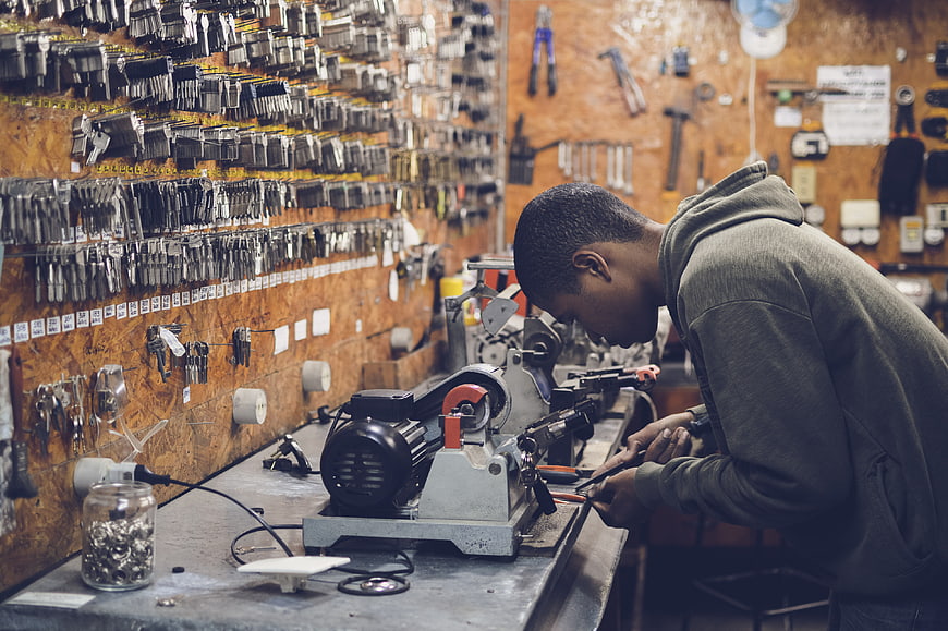 Locksmith working with key cutting machine in workshop