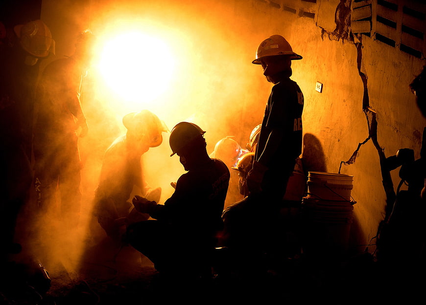 Silhouetted Rescuers Working in Smoke and Firelight at Night
