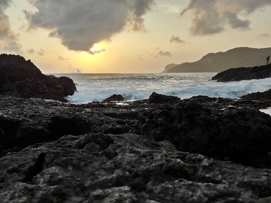 Dramatic sunset over rocky coastline with crashing waves
