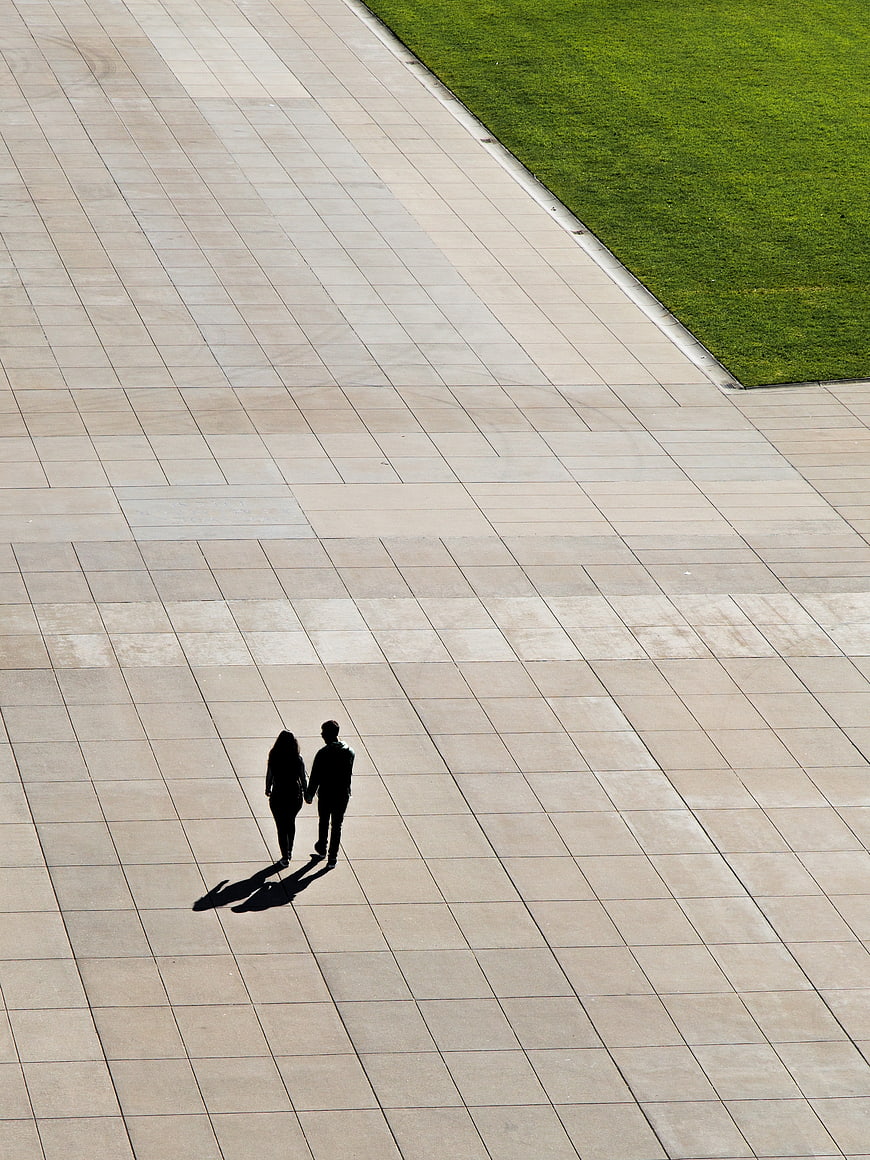 High angle view of couple walking on paved plaza