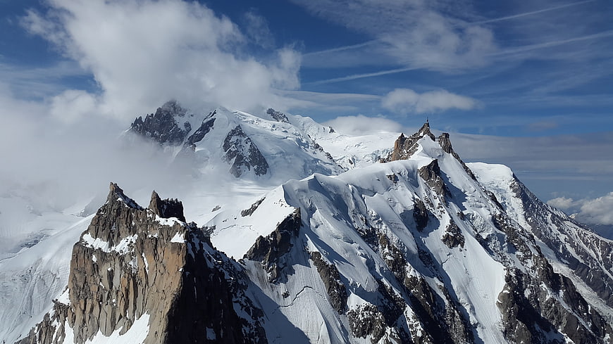 Snowy Mountain Peaks with Clouds and Blue Sky
