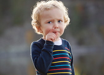 Curious toddler with finger in mouth thinking