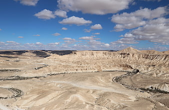 Vast desert landscape with eroded hills and blue sky