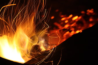 Close-up of glowing campfire sparks and flames at night