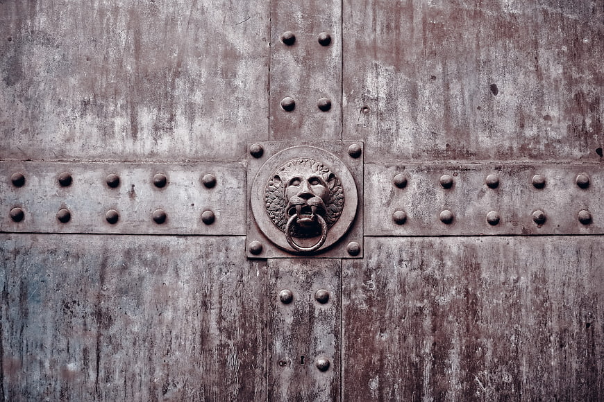 Close-up of antique wooden door with lion head bronze knocker
