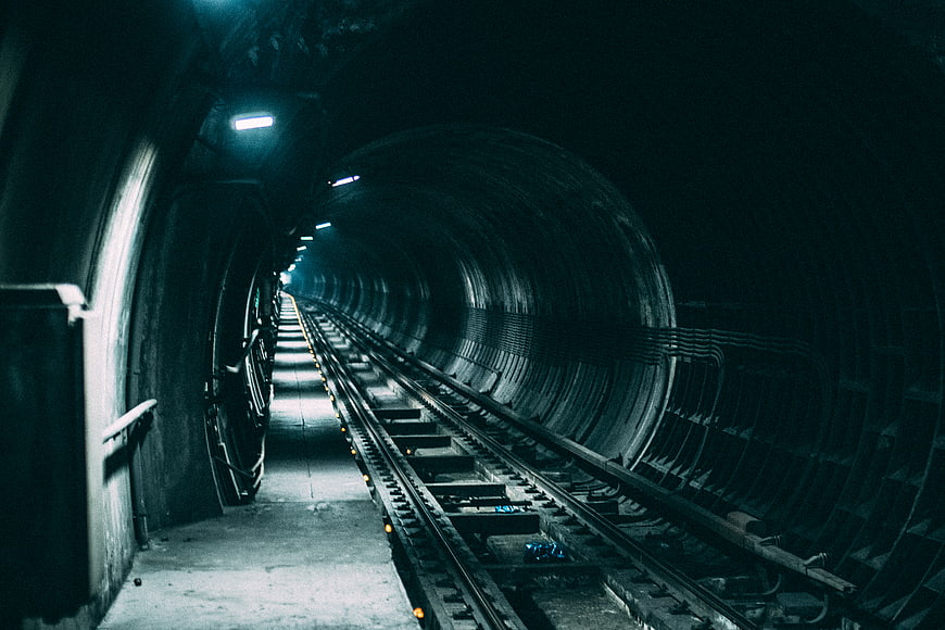 Dark subway tunnel with tracks and blue lighting
