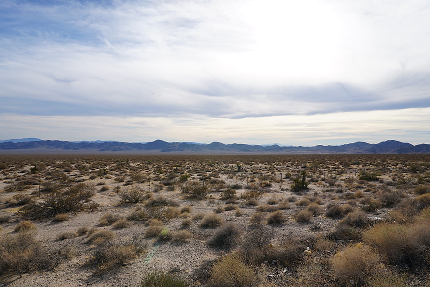 Vast desert landscape with distant mountains and cloudy sky