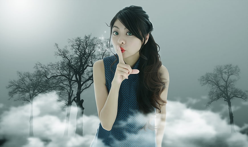 Mysterious Asian woman making shushing gesture in foggy forest