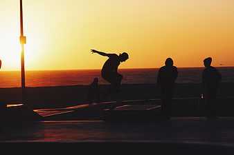 Skateboarder Silhouette Jumping at Sunset Beach