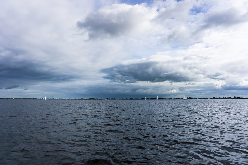 Sailboats on a wide river under a dramatic cloudy sky