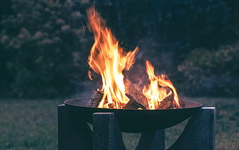 Campfire burning in metal fire pit at dusk