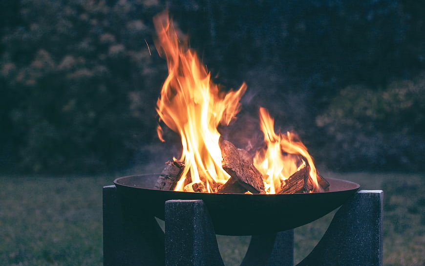 Campfire burning in metal fire pit at dusk