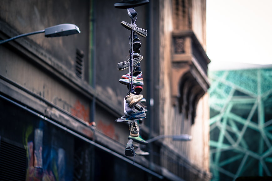 Stack of shoes hanging from street lamp in urban alley