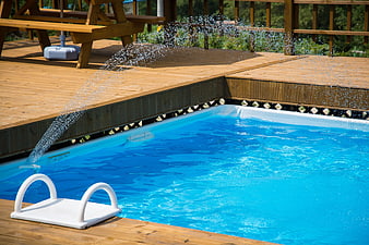 Water filling above ground pool on wooden deck