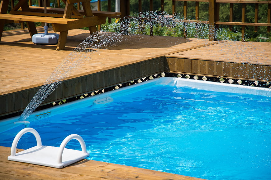Water filling above ground pool on wooden deck