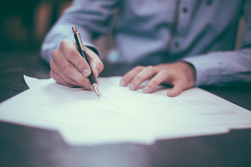 Close-up of Man Signing Business Document with Pen