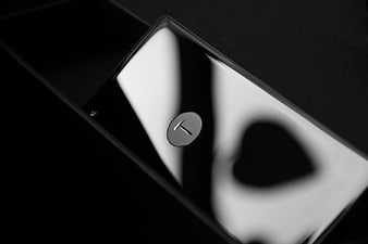 Close-up of black smartphone with T logo and light reflection