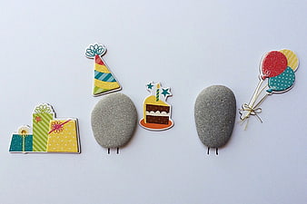 Cute stone characters with birthday party accessories flat lay