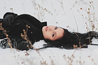 Woman lying in snow with dried plants