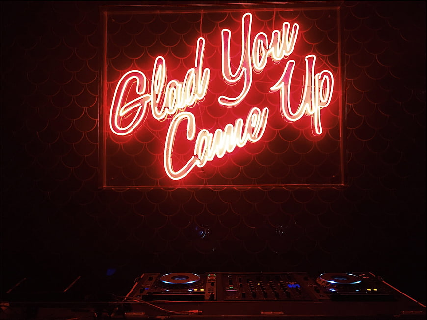 Red Neon Sign and DJ Equipment in Dark Club