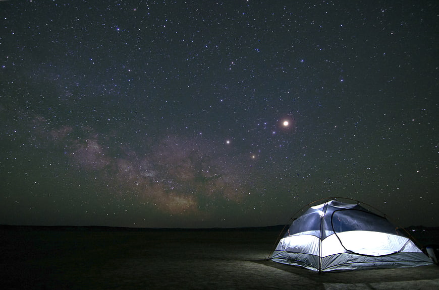 Illuminated camping tent under the Milky Way night sky