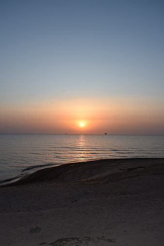 Serene Sunrise Over Calm Sea with Sandy Foreground