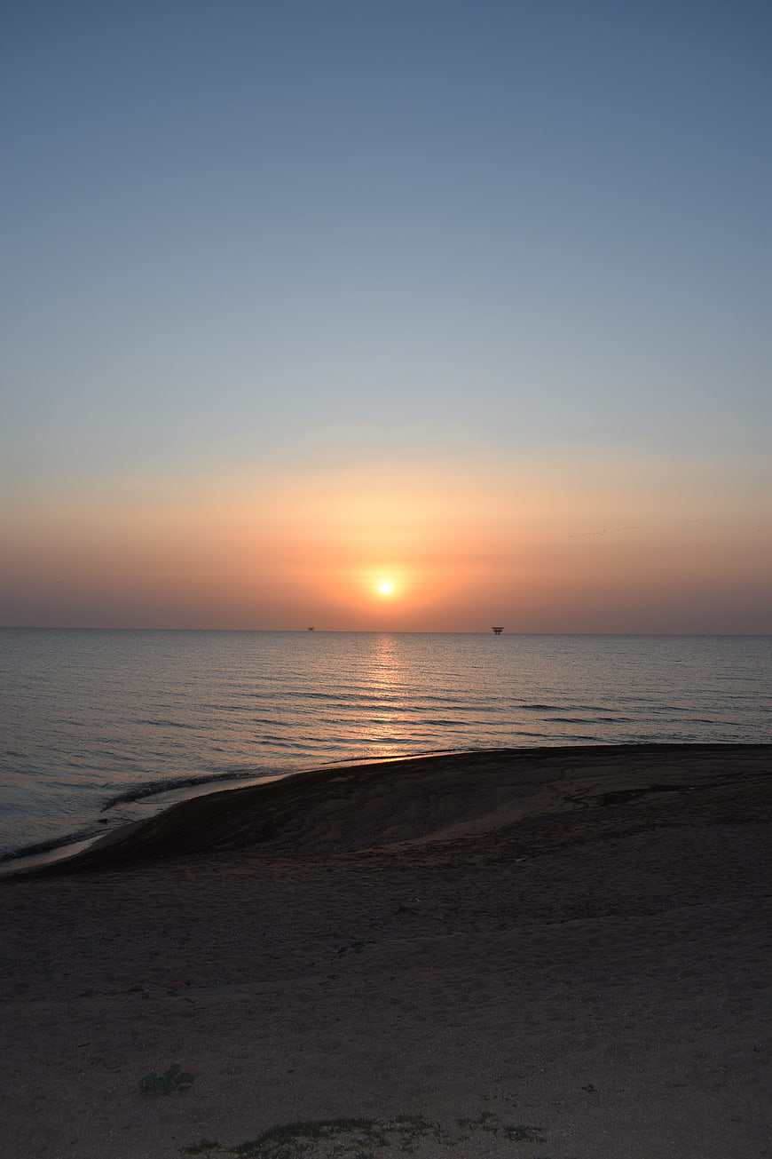 Serene Sunrise Over Calm Sea with Sandy Foreground