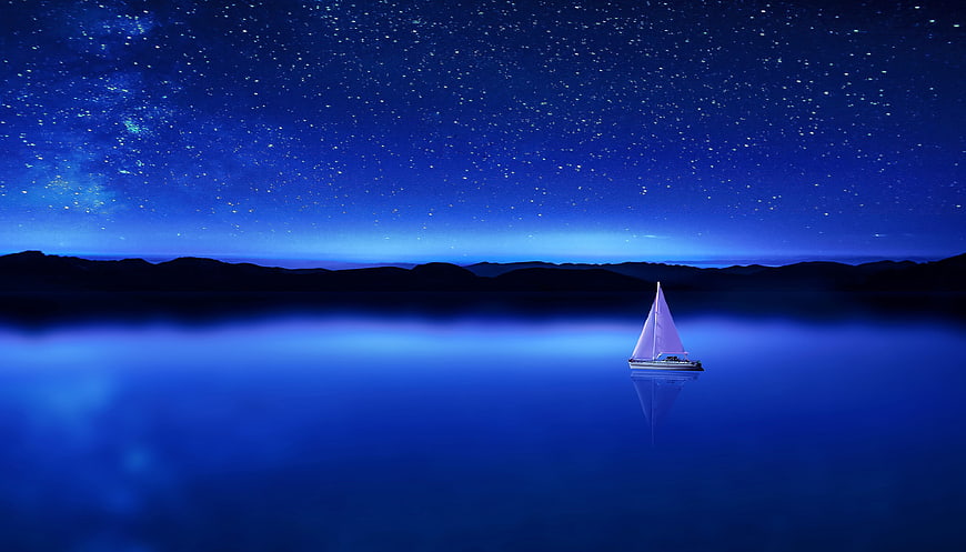 Sailboat on calm blue water under starry night sky
