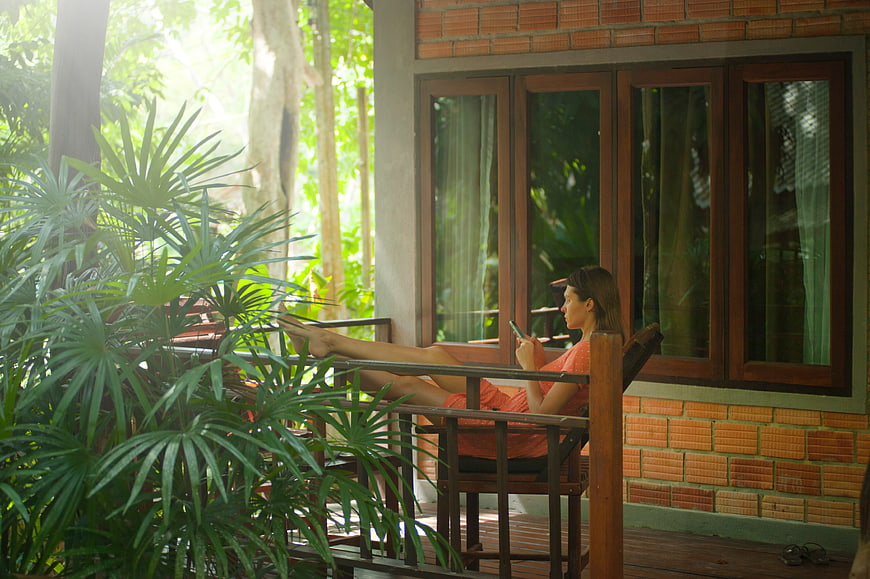 Woman relaxing on wooden porch with smartphone