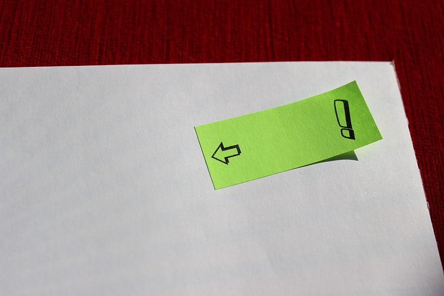 Green sticky note with arrow on white paper