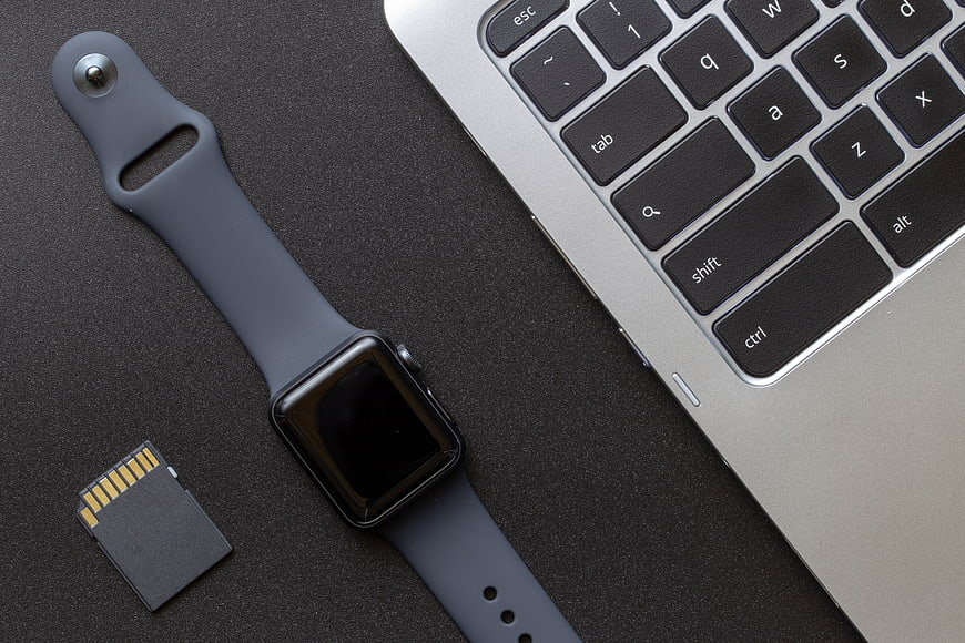 Smartwatch, laptop, and memory card on dark textured surface