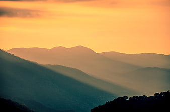 Misty Mountain Range at Golden Sunset with Atmospheric Haze