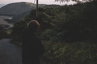 Man standing on rural road overlooking coastal landscape