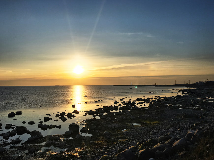 Golden Sunset Over Rocky Shoreline With Calm Ocean Horizon