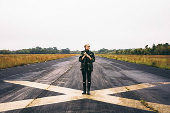 Woman standing on abandoned runway with X marking