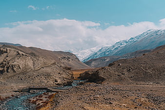 Scenic mountain river valley with bridge and snow-capped peaks