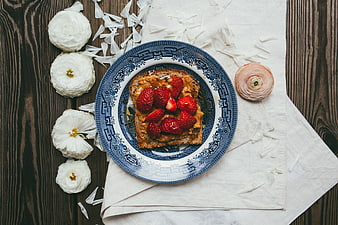 Flat lay of strawberry toast on blue patterned plate with flowers