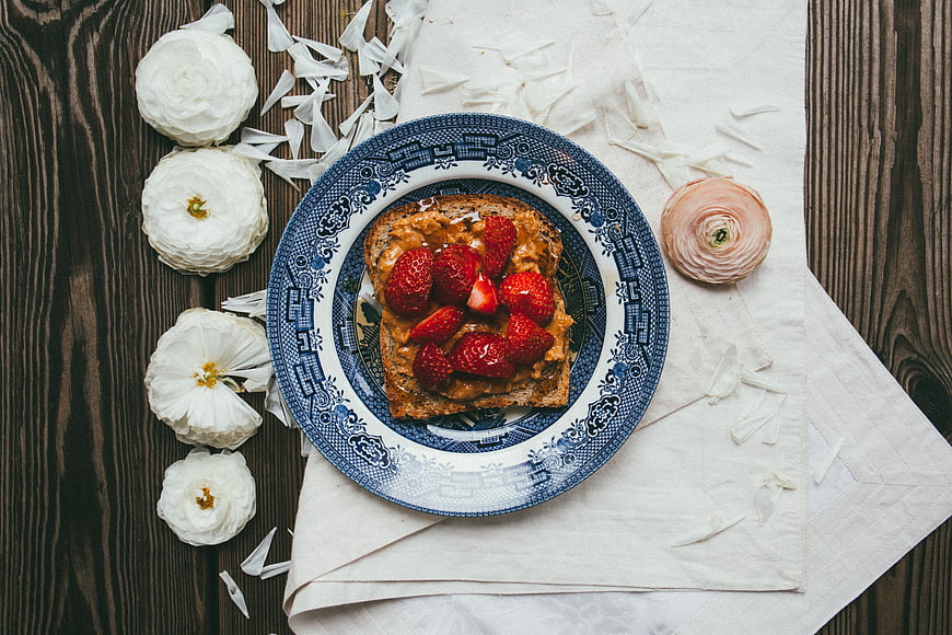 Flat lay of strawberry toast on blue patterned plate with flowers