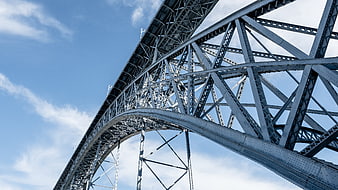 Low angle view of steel bridge truss against blue sky