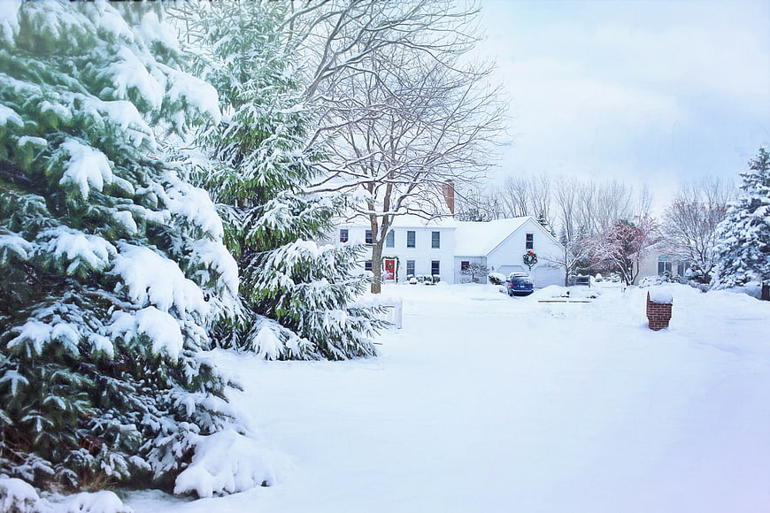 Snowy Winter House with Christmas Wreath and Pine Trees